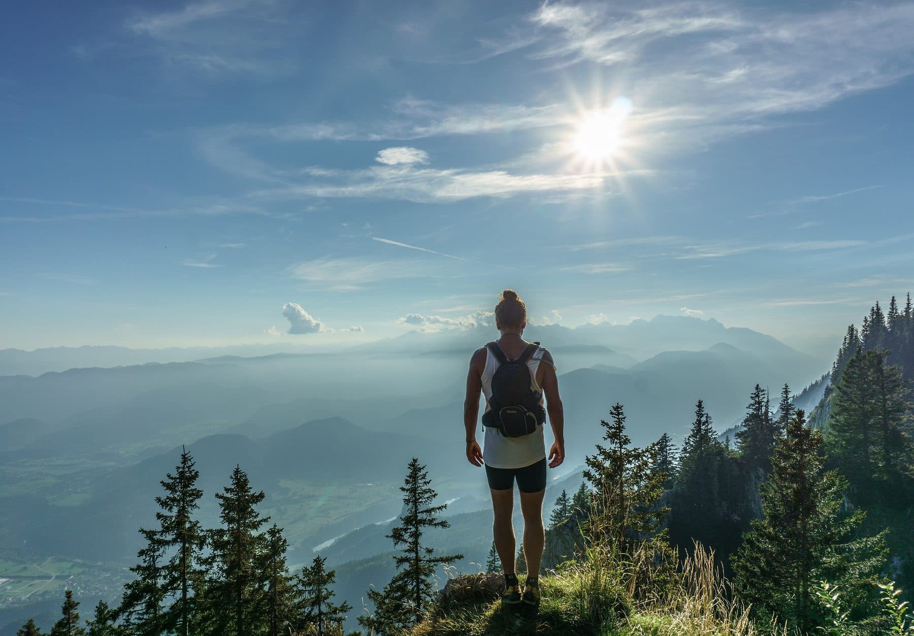 A hiker from behind looking over a forested valley