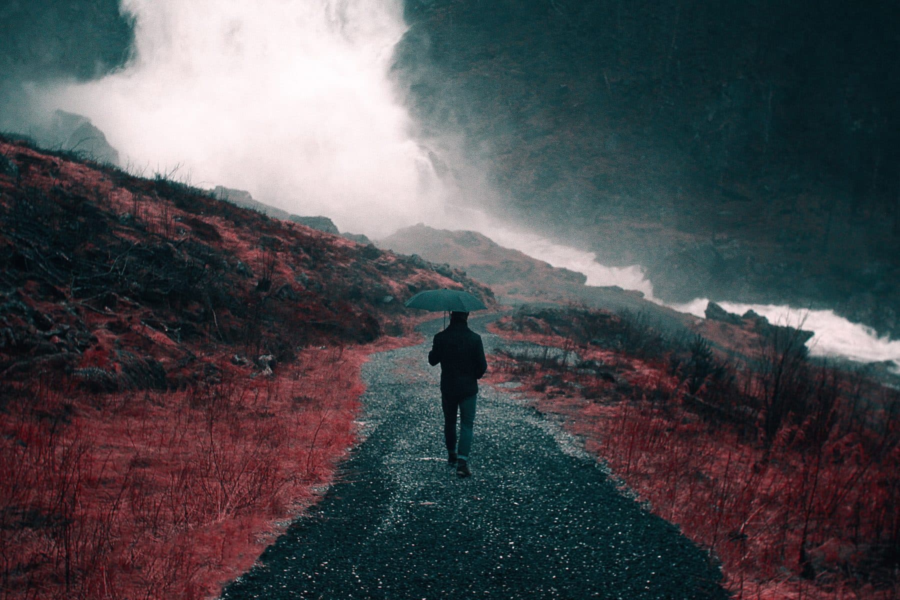 A person walking a gravel road toward low cloud